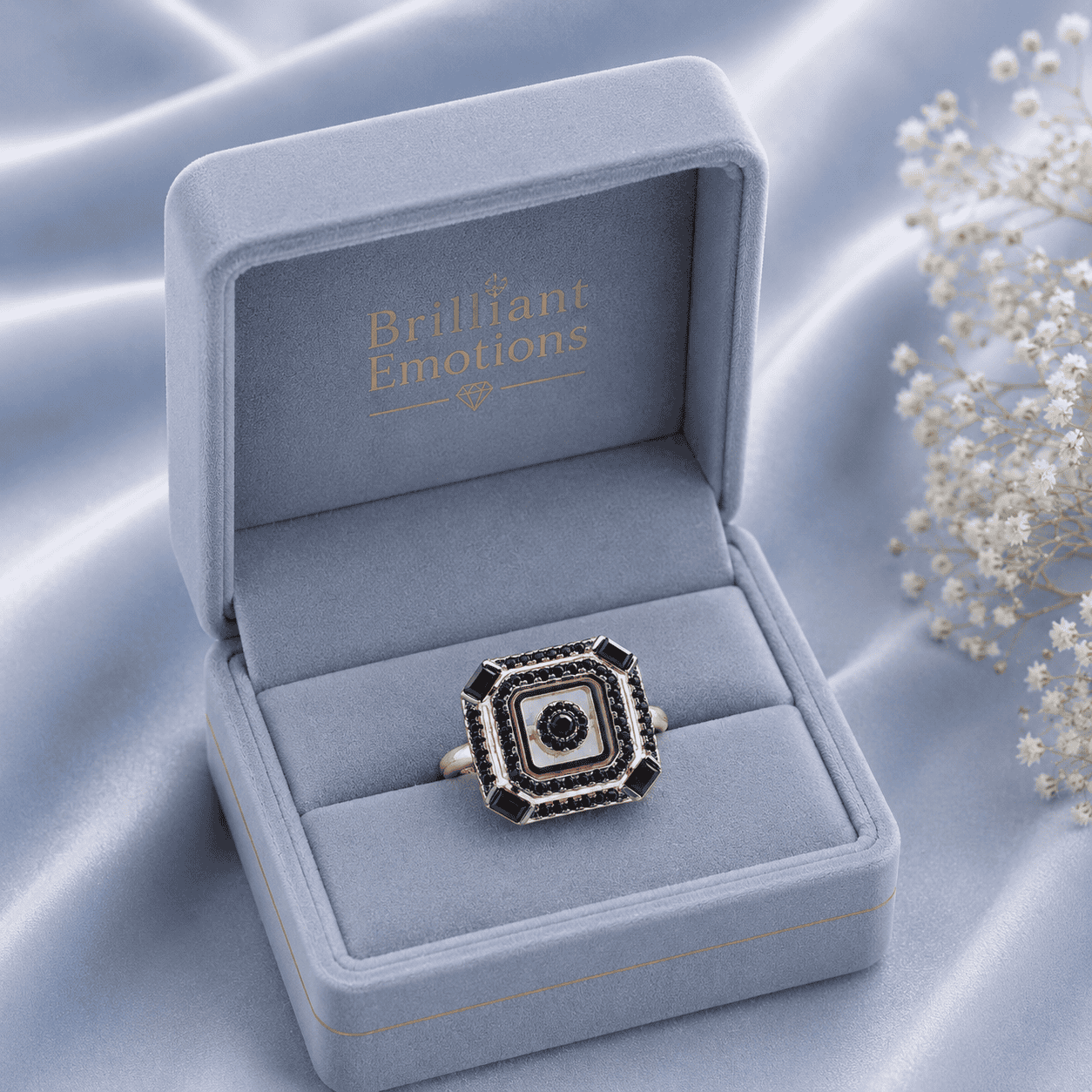 Eleganter Schmuckring in blauer Geschenkbox mit weißen Blumen.